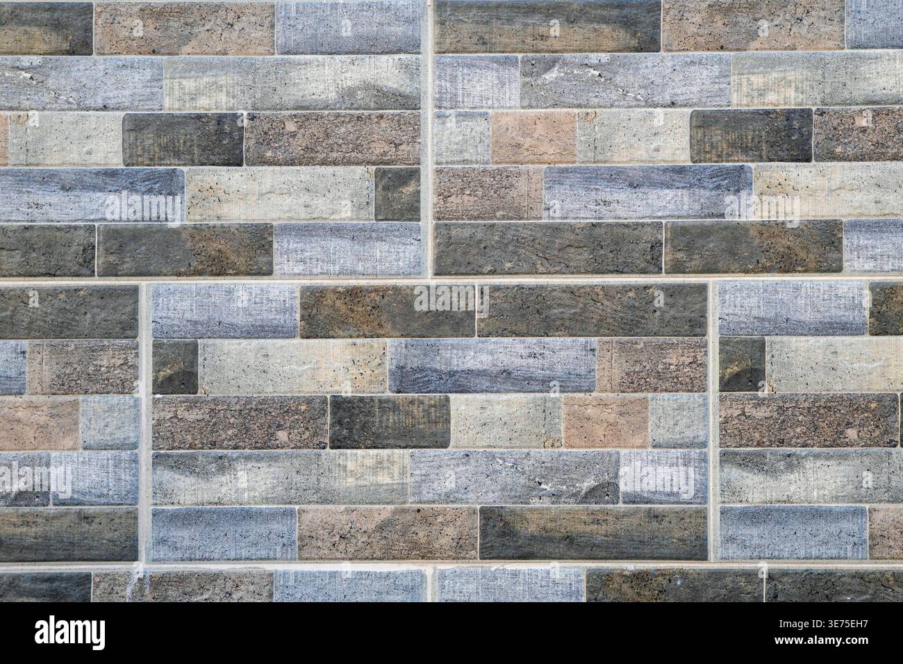 Modern wall cladding made of multicolored rectangular stone tiles. Stock Photo
