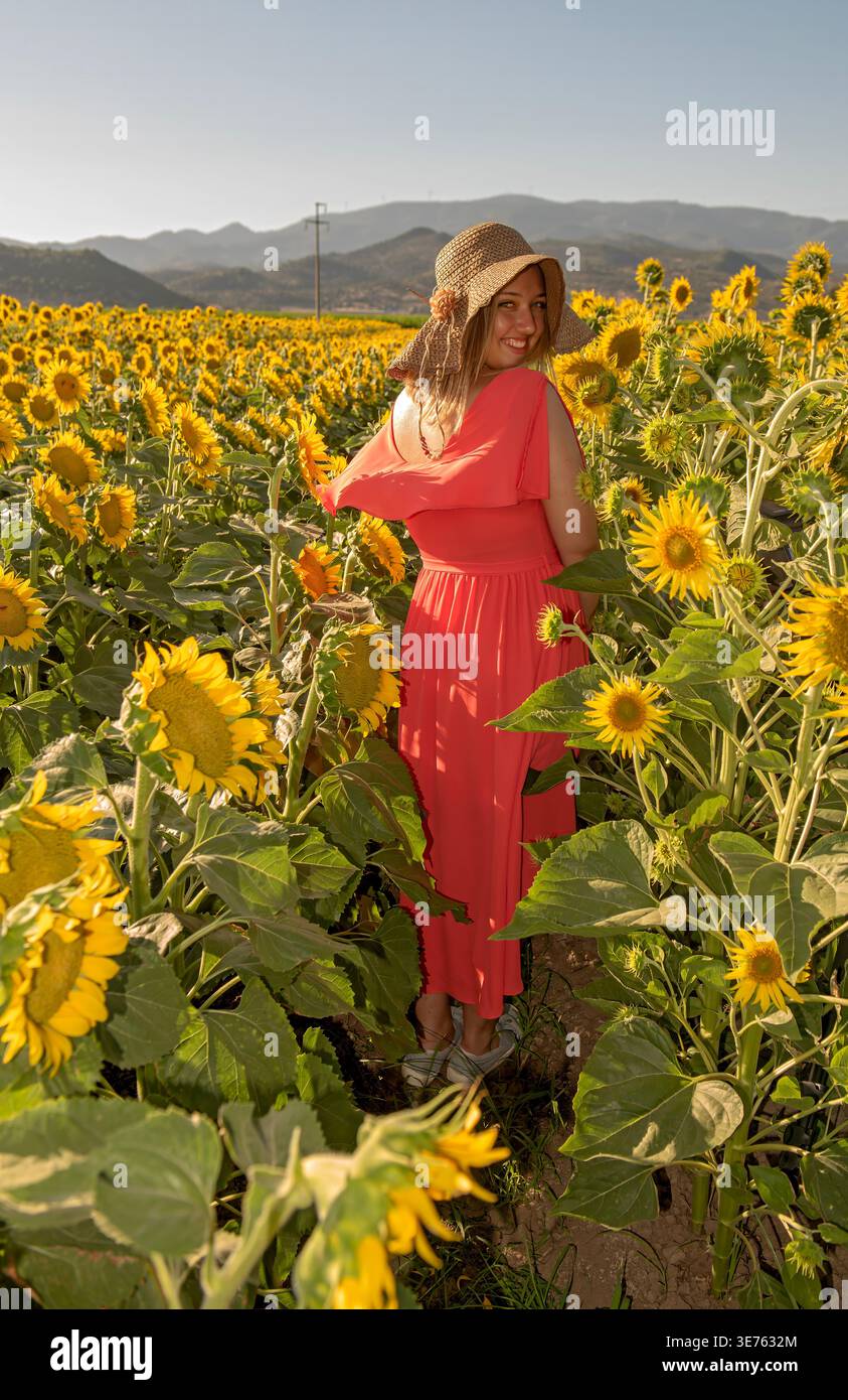 Happy woman in red dress looking back in blooming sunflowers. BERGAMA,  IZMIR, TURKEY - July 12, 2020: Vibrant summer lifestyle portrait Stock  Photo - Alamy