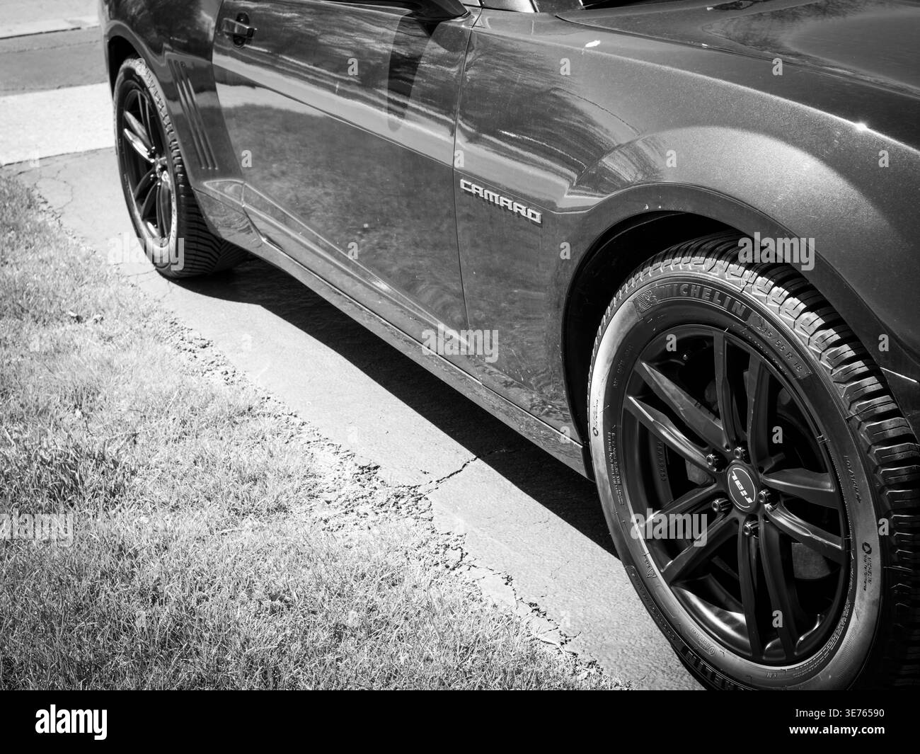Black Chevrolet Camaro with Michelin tires parked curbside, detailed side panel and alloy wheels in monochrome automotive closeup Stock Photo