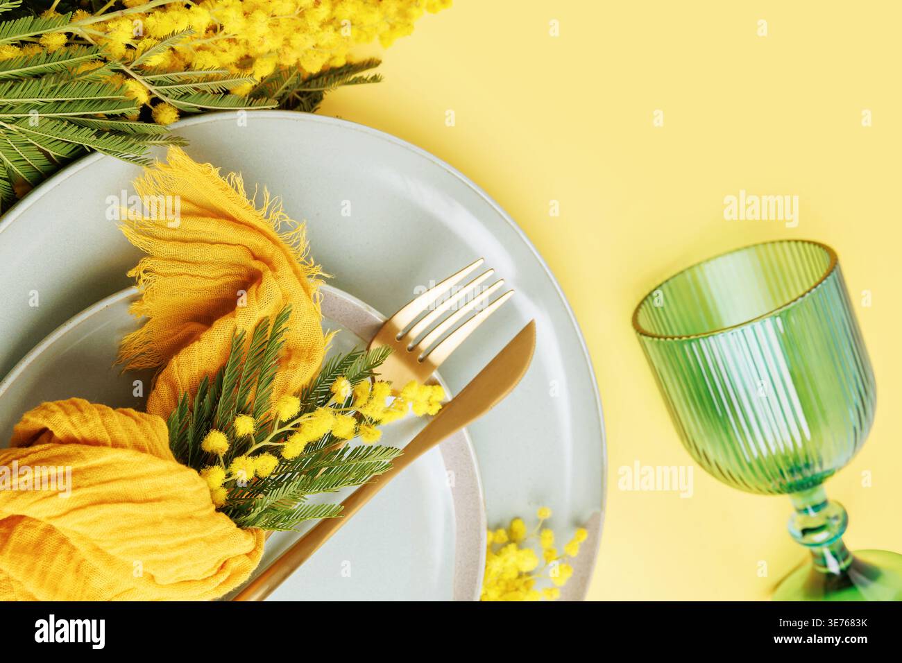 Spring dining composition with mimosa flowers and pastel tableware Stock Photo