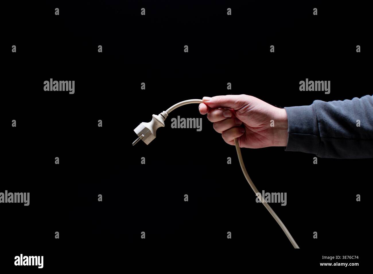 Hand holding cable with power connector Stock Photo