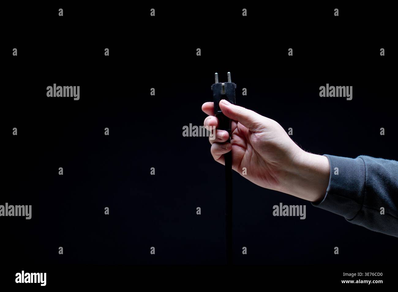 Hand holding black electric plug close up Stock Photo