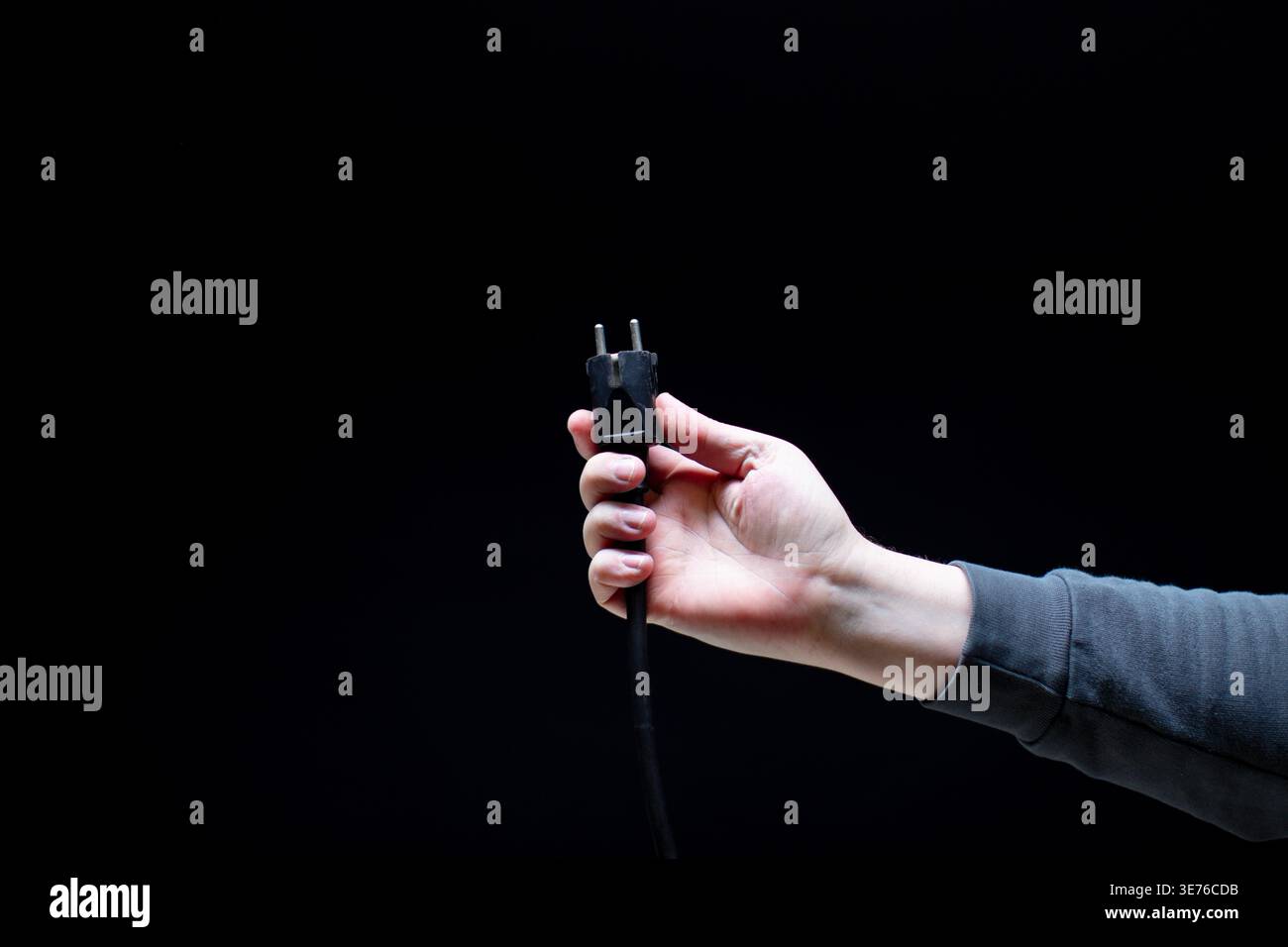 Hand holding black electric plug close up Stock Photo
