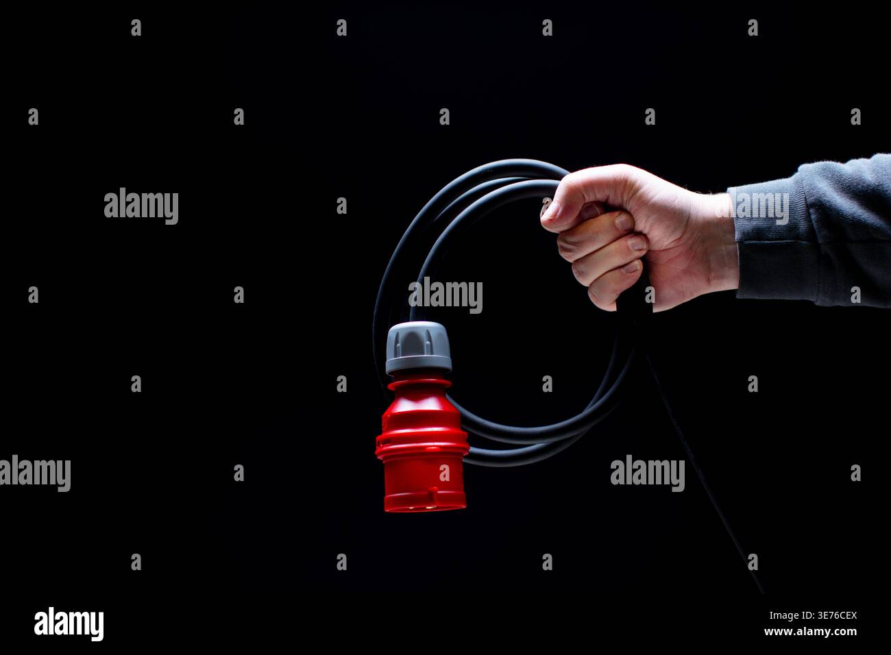 Hand holding red power connector on black background Stock Photo
