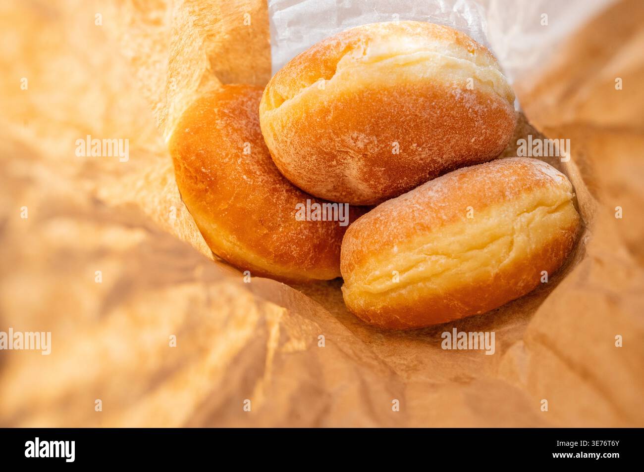 Freshly baked berliner donuts with powdered sugar in a brown paper craft bag, close up Stock Photo