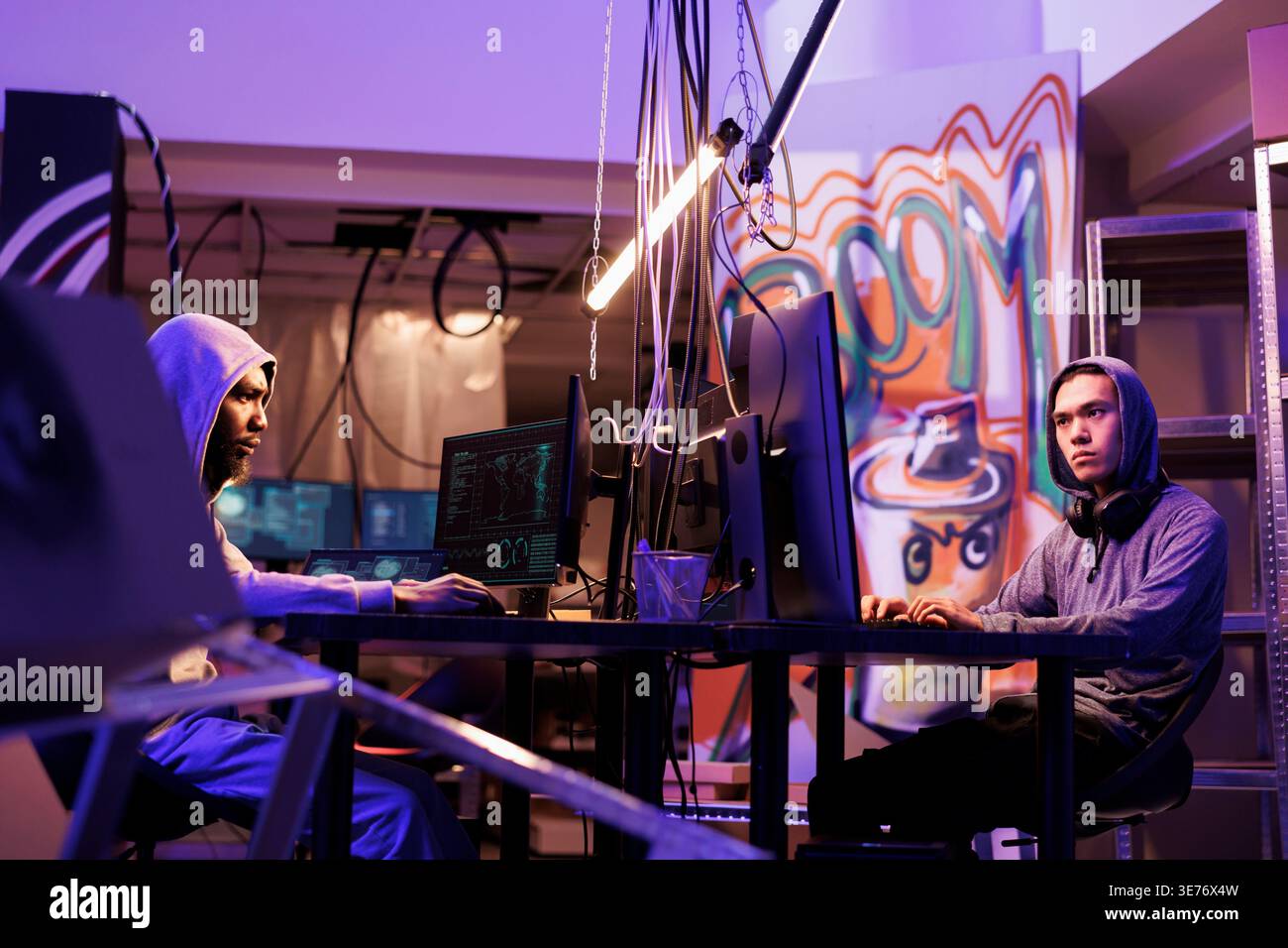 Hackers breaking law while coding dangerous computer virus in abandoned warehouse. Criminals working together and programming illegal malicious software in hideout workspace Stock Photo