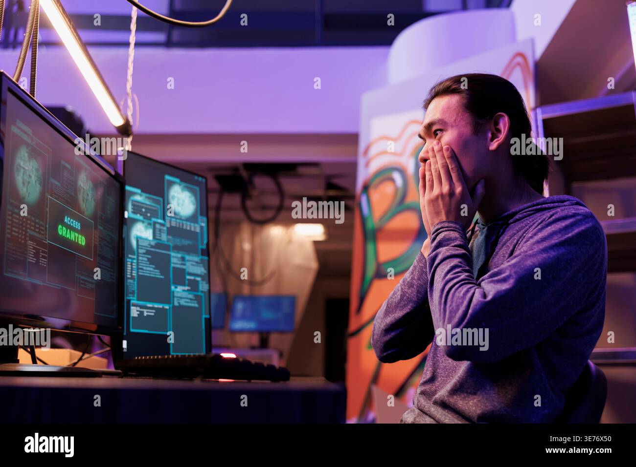 Excited hacker getting access granted while breaking into database server. Happy shocked young asian criminal hacking system successfully while doing illegal activities at night Stock Photo
