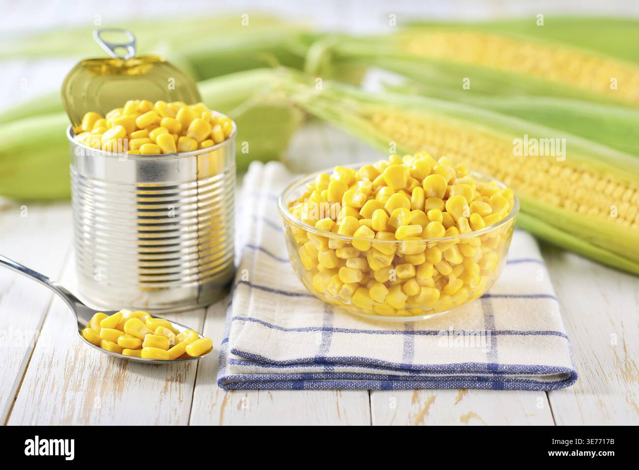Canned young corn grain in a clear glass bowl on a white table, selective focus Stock Photo