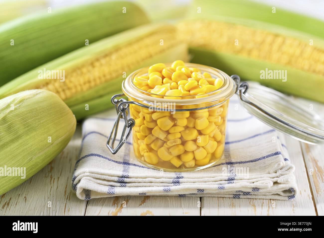 Canned sweet corn in jar on a white table, selective focus Stock Photo