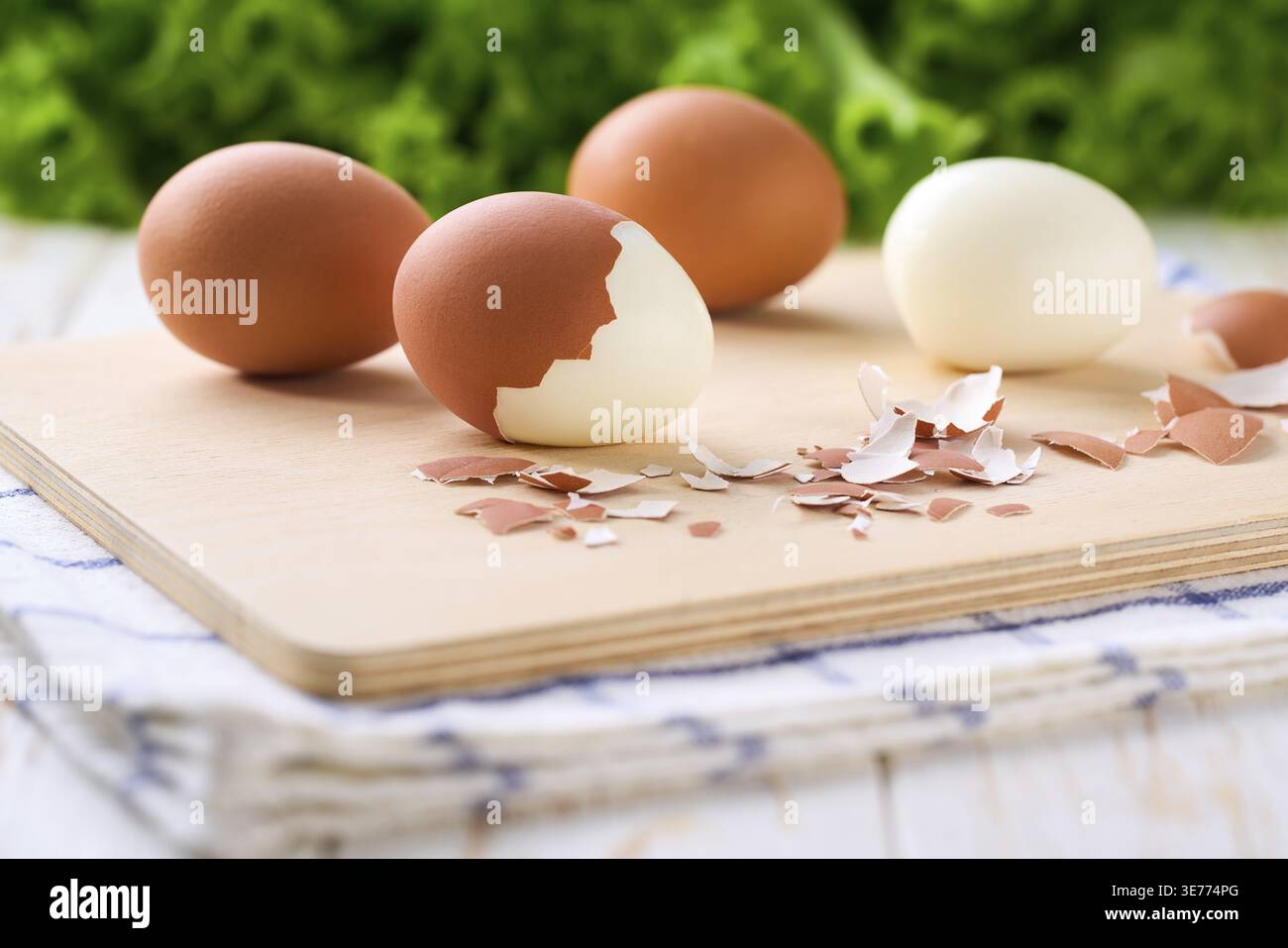 Fresh hard boiled eggs with shell beside in a cutting board, selective focus Stock Photo