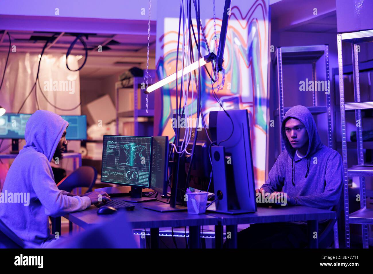 Hackers collaborating while coding virus software, doing illegal activities and breaking law in abandoned warehouse. Criminals programming malware on computers in hideout place Stock Photo