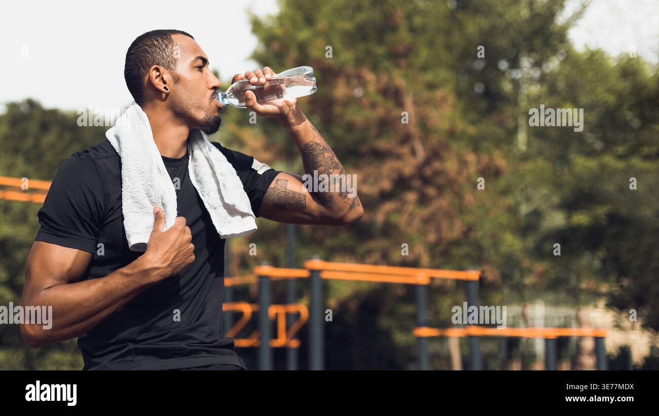 Sporty man drinking water after workout outside Stock Photo