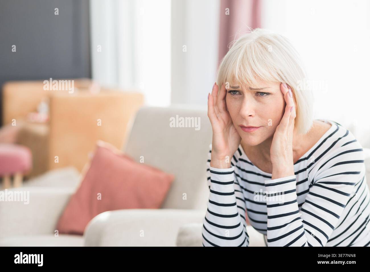 Woman suffering from headache, sitting at home Stock Photo