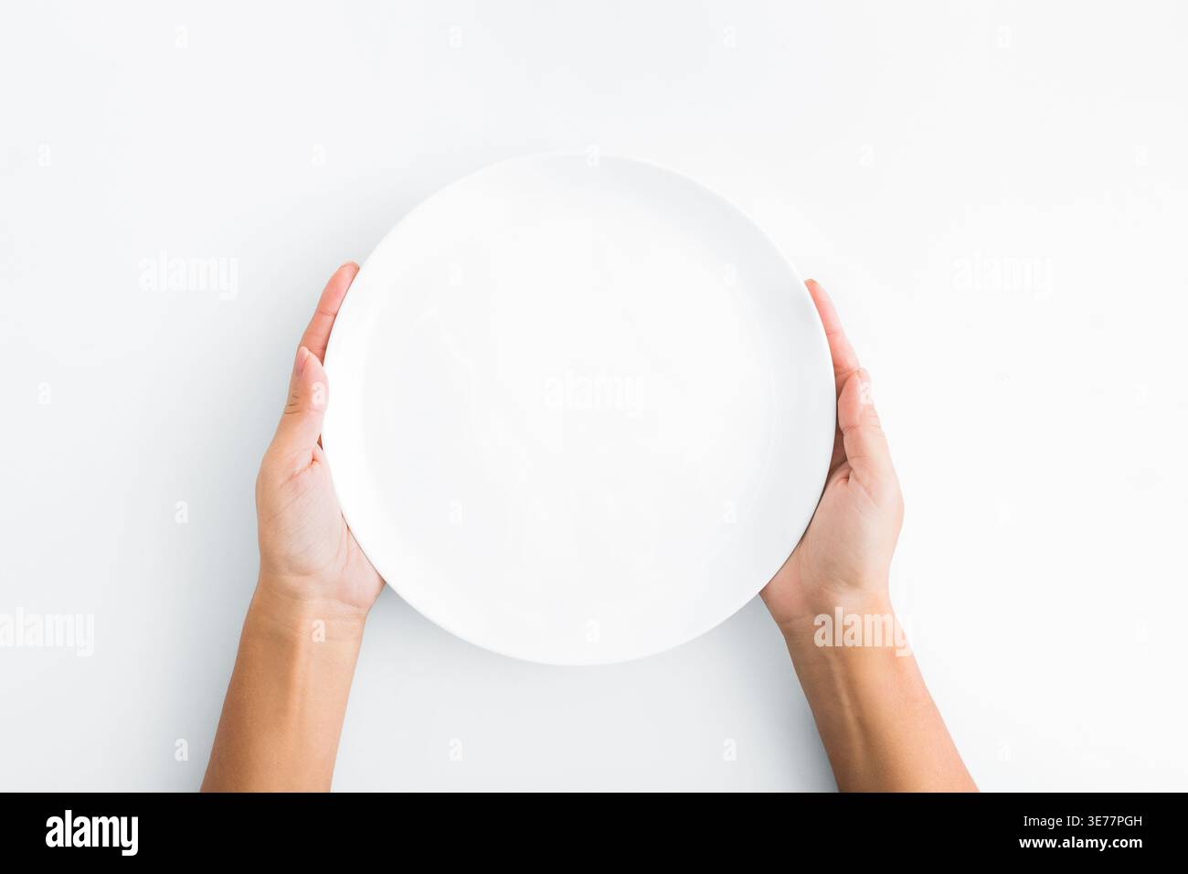Female hands holding empty plate on white background Stock Photo
