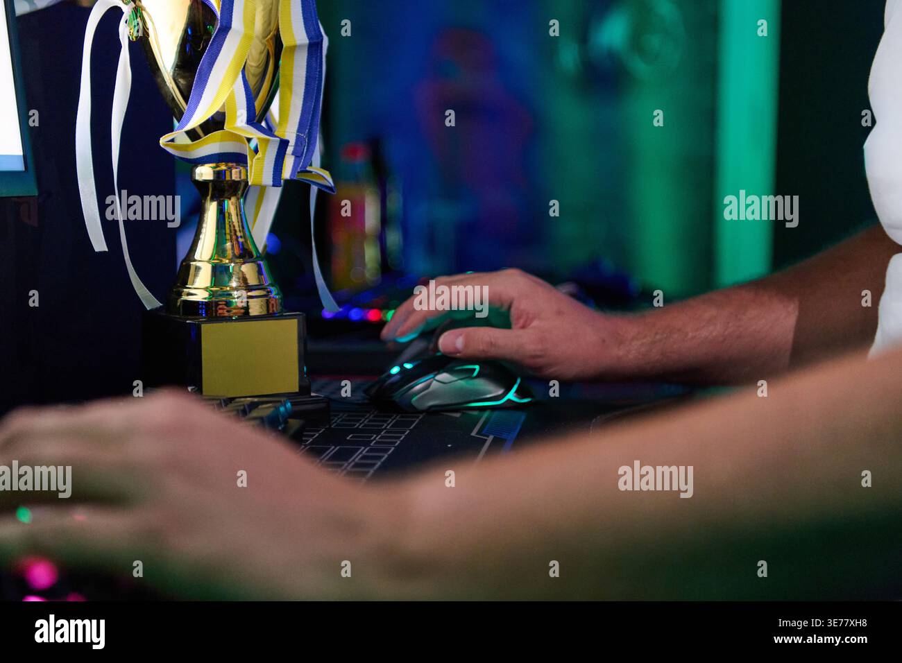 Gamer Hands Using Mouse Beside Trophy After Victory in Competitive Esports Tournament Setup Stock Photo