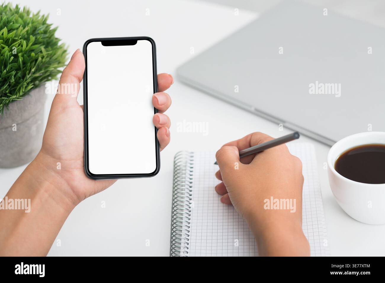 Fmale student hand writing on notebook and using smartphone Stock Photo