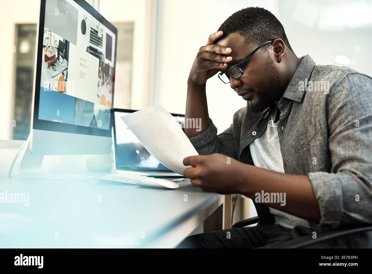 Computer screen, documents and stress with web designer black man in office for problem solving. Paperwork, pc and reading with African developer at Stock Photo