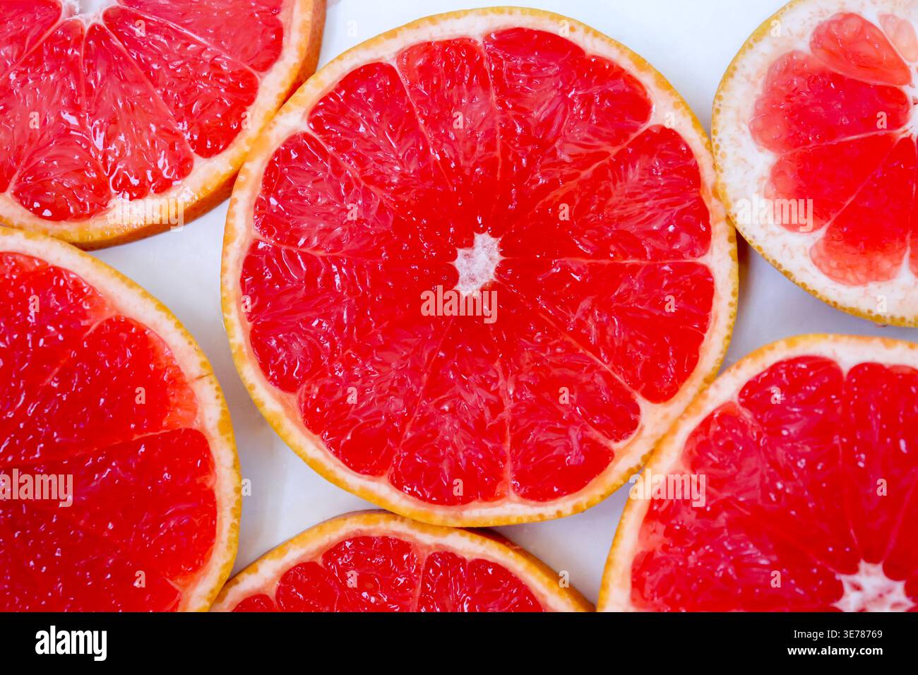 Freshly cut grapefruit slices isolated on a white background, bright pink or red citrus fruit pieces with juicy texture, healthy natural food concept. Stock Photo
