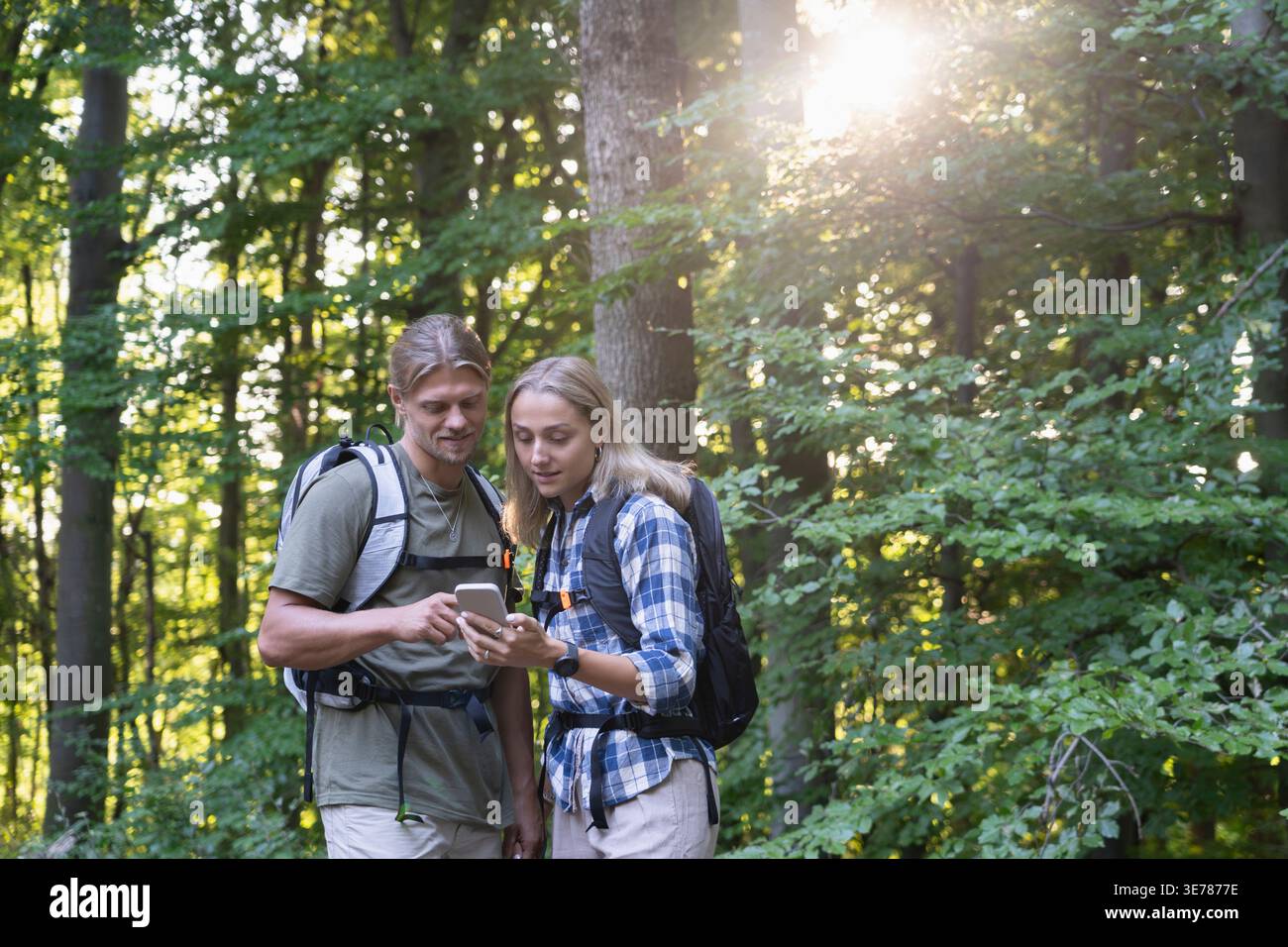 Young couple checking smartphone map together in forest Stock Photo
