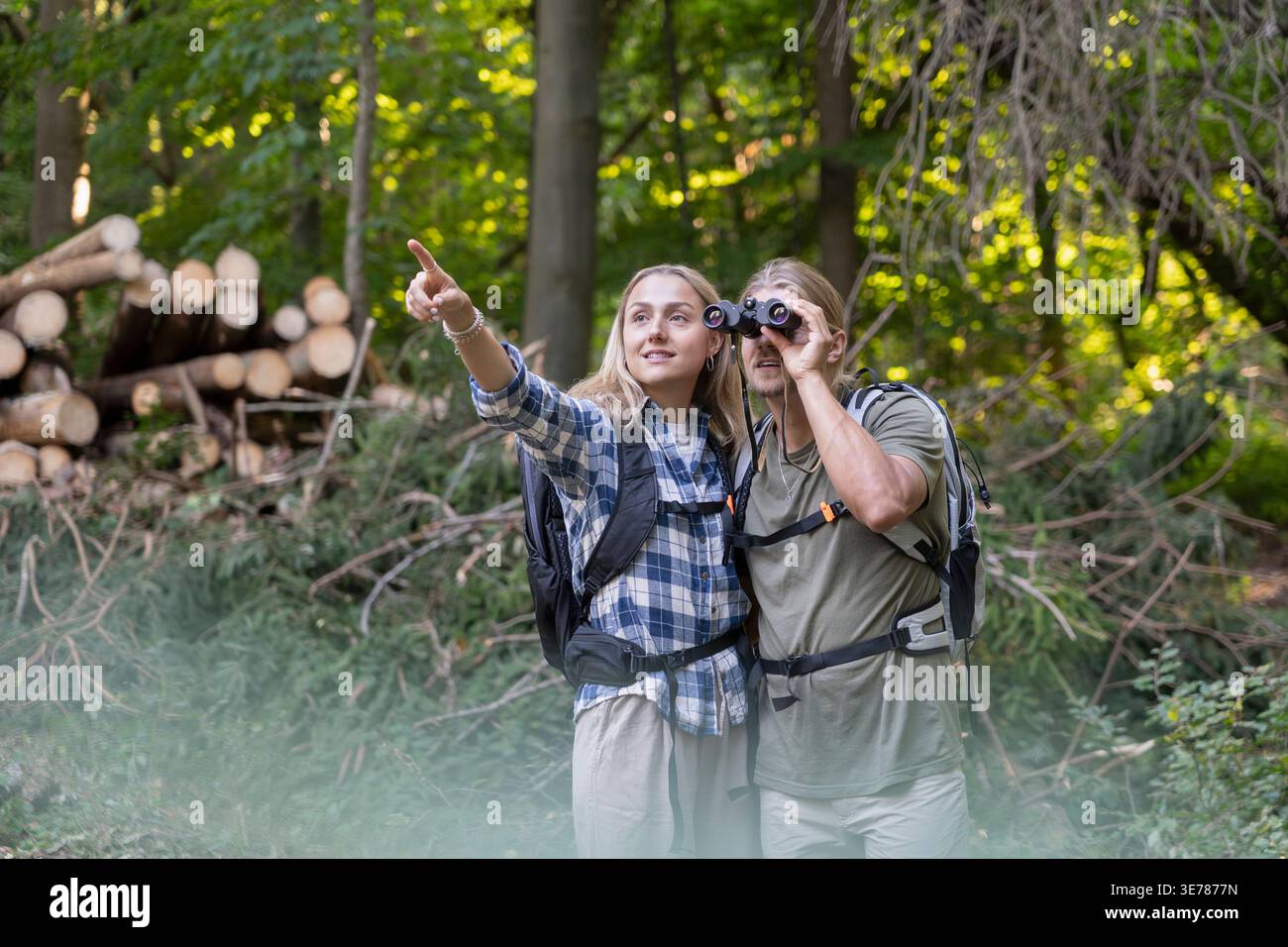 Couple observing nature with binoculars pointing into forest Stock Photo