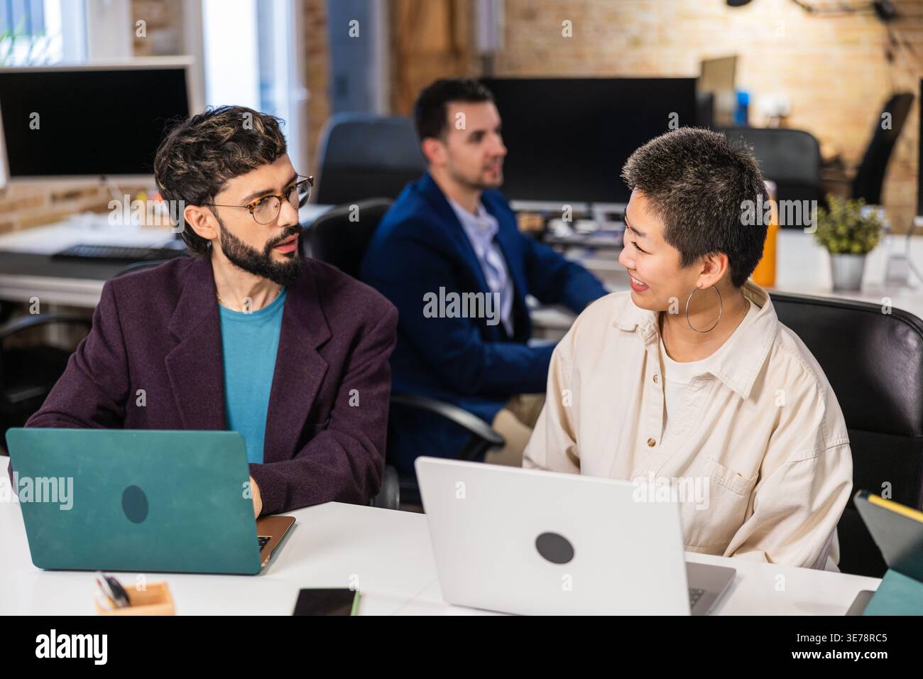 Multi ethnic team collaborating on project using laptops in modern office Stock Photo