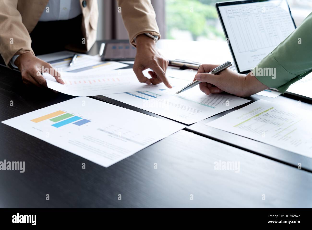 In Marketing brainstrom meeting The team is standing and pointing at the marketing plan from which data has been collected to be used as information g Stock Photo