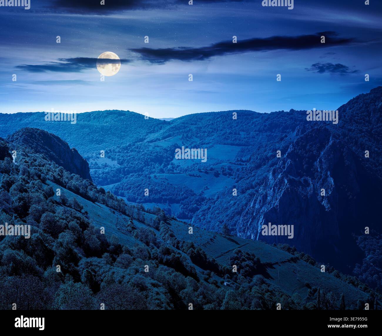 beautiful countryside at night. full moon over wonderful springtime landscape in mountains. grassy field and rolling hills. rural scenery with steep f Stock Photo