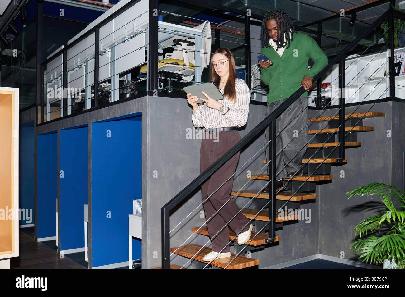 Business Colleagues Descending Stairs While Using Mobile Devices Stock Photo