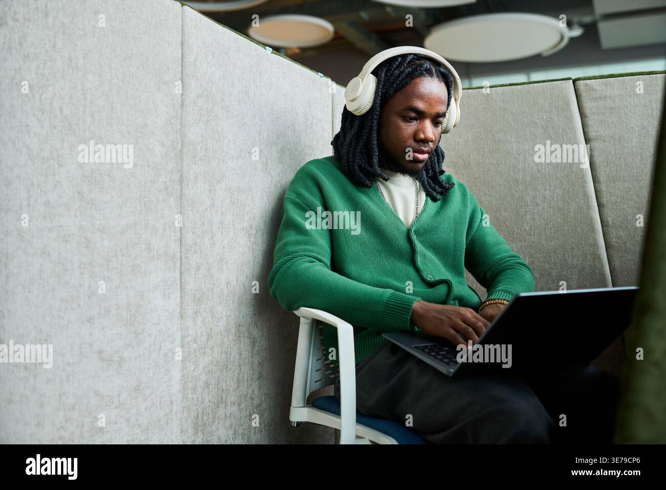 Black Man Using Laptop and Headphones for Focused Office Work Stock Photo