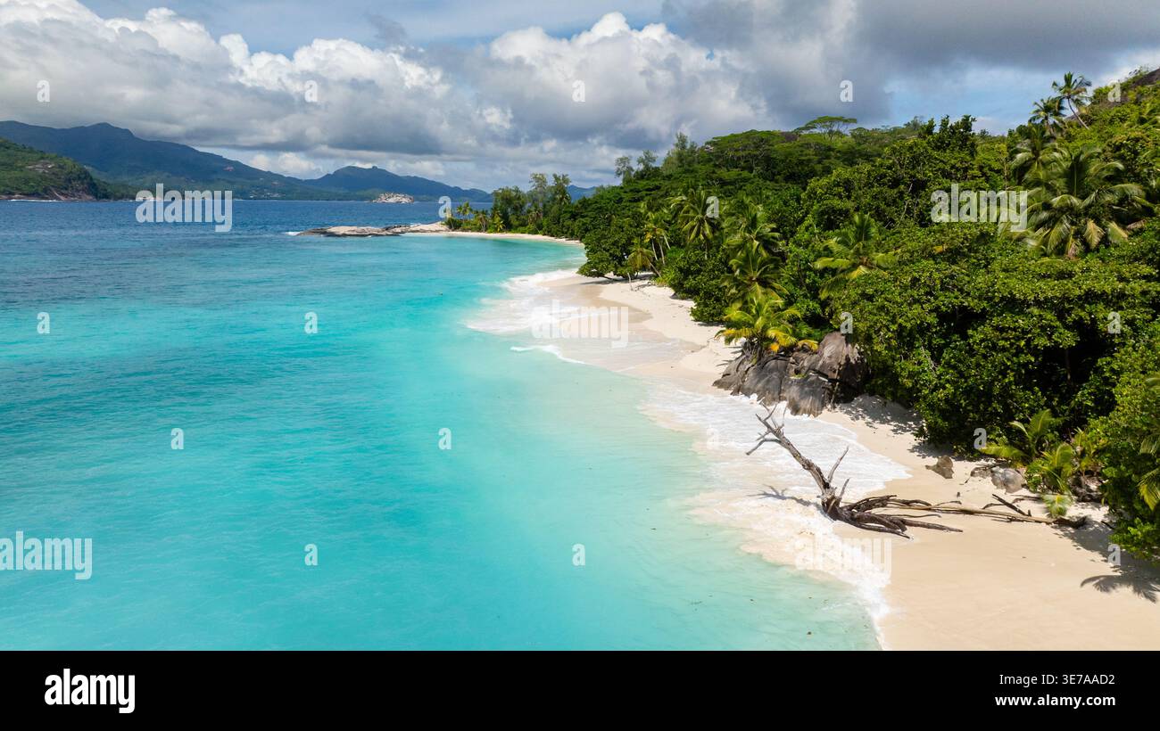 Green hills extending to the turquoise ocean, with lush vegetation and blue skies. Therese. Seychelles, Mahe. Stock Photo