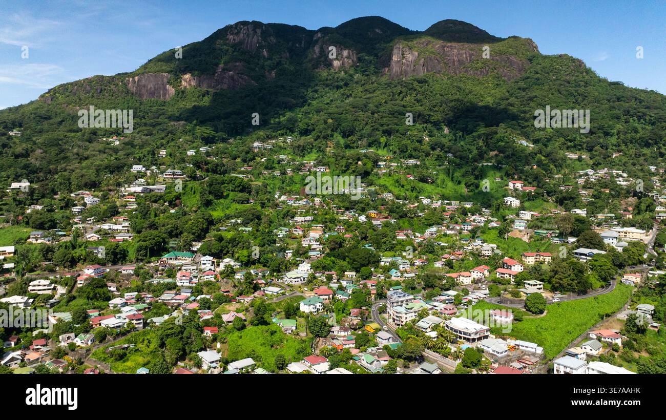 Aerial view of town surrounded by green hills under a clear blue sky. Victoria. Seychelles, Mahe. Stock Photo