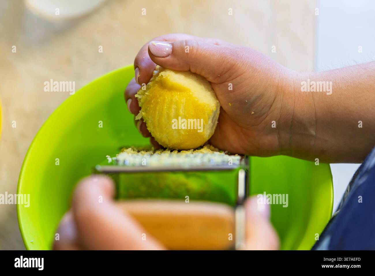 Grating Fresh Lemon Zest into a Green Bowl Close-up Stock Photo