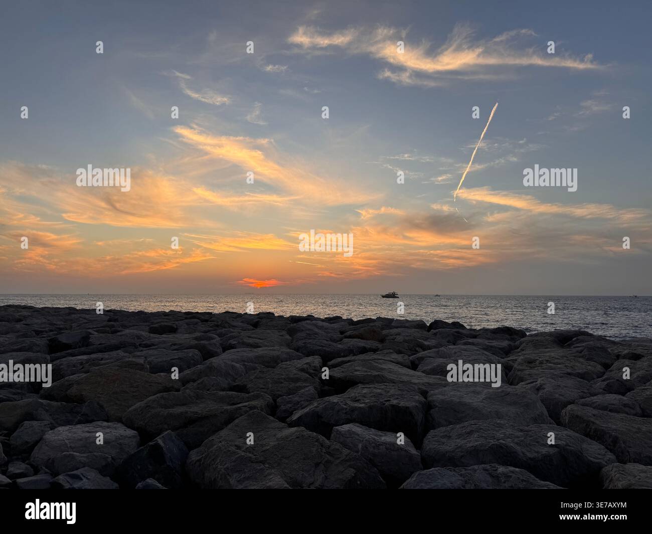 Dramatic coastal landscape at sunset with vivid sky and textured rocky shoreline - Smartphone Captured Stock Image