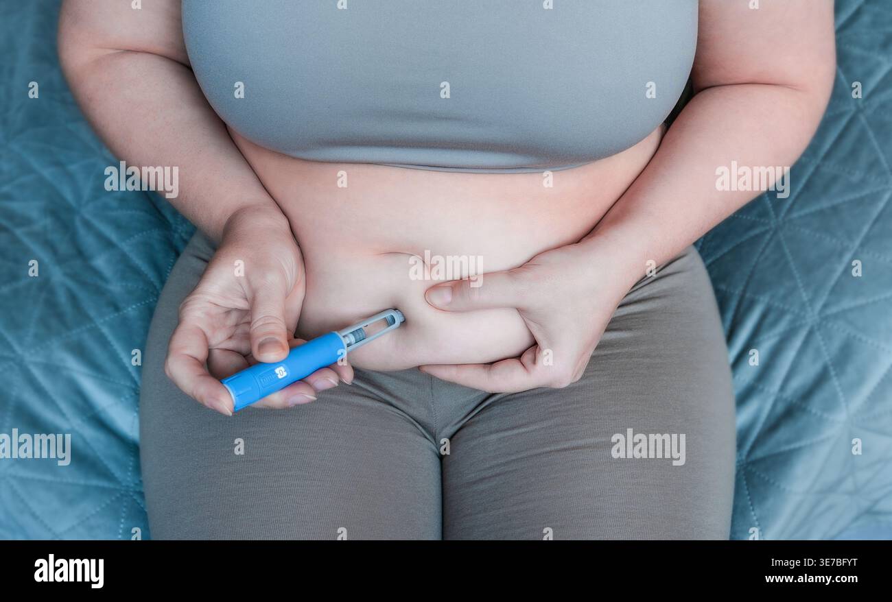 woman injecting a GLP-1 weight loss medication into belly fat Stock Photo -  Alamy