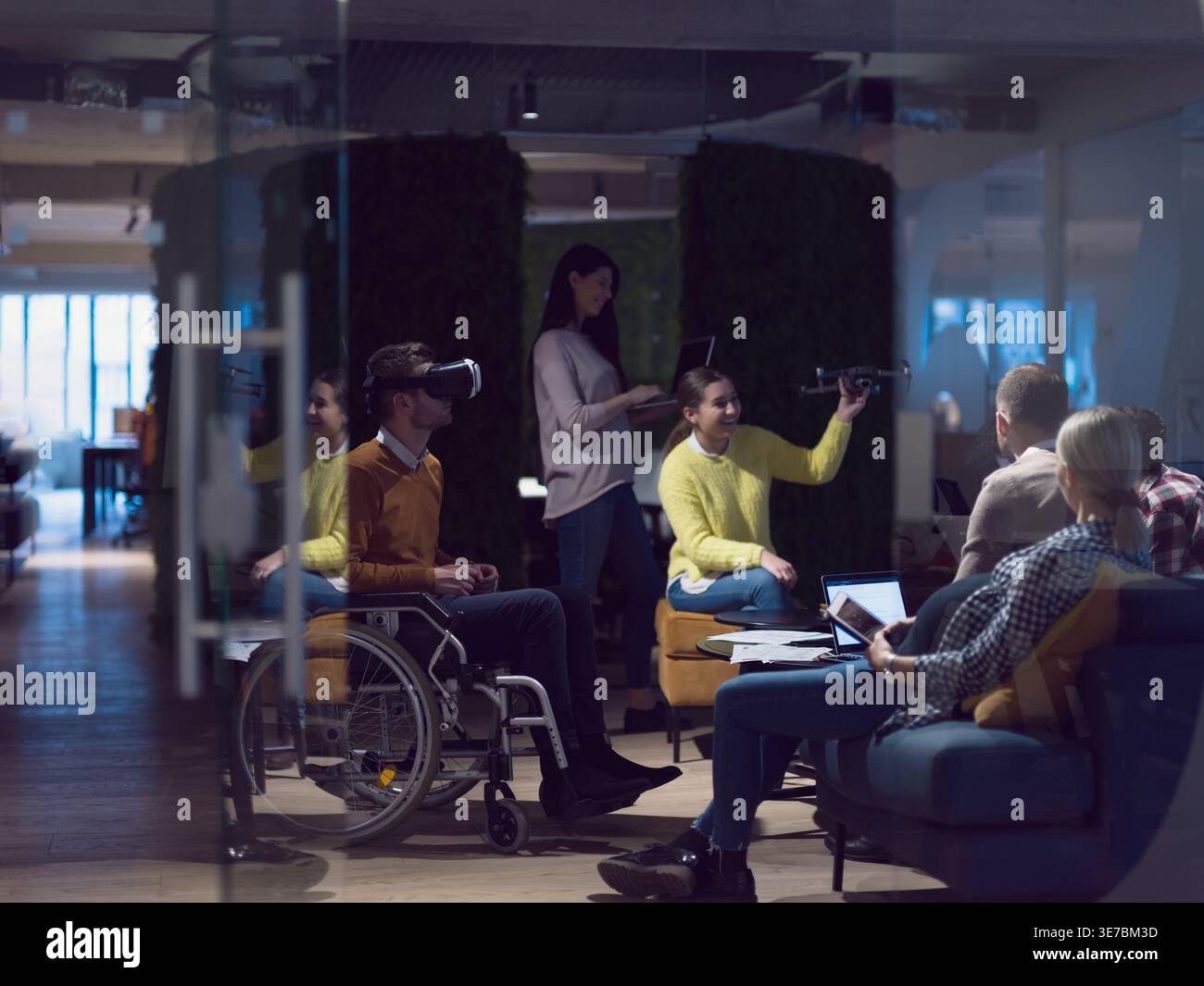 Diverse group of business people with disabled caucasian businessman using VR goggles and drone assistance simulation while having a meeting in the... Stock Photo