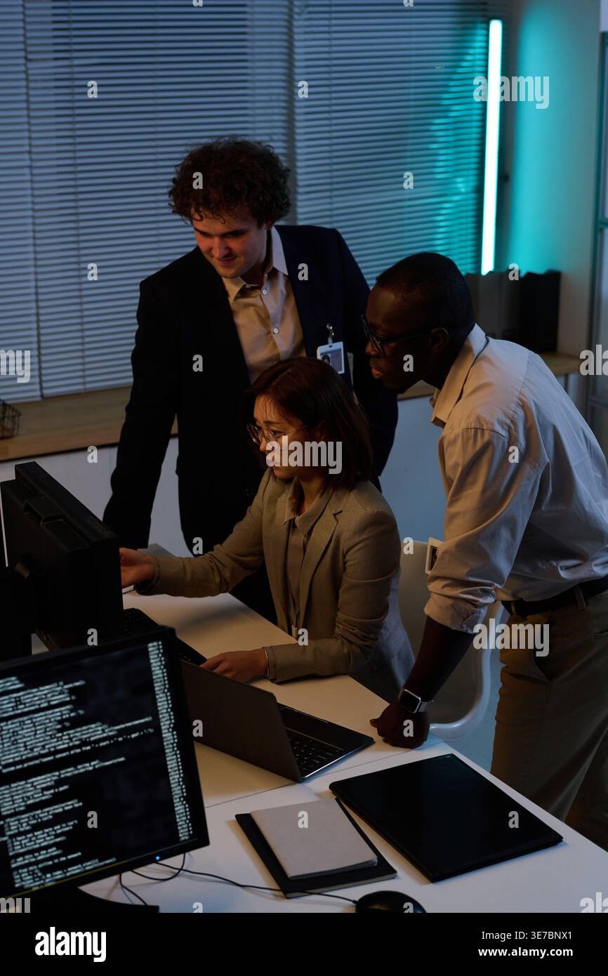 Diverse group of programmers developing new code for computer program together working overtime in office Stock Photo