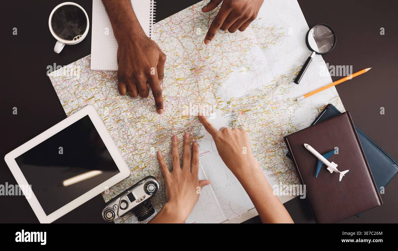 Black couple pointing on map planning vacation trip at home Stock Photo