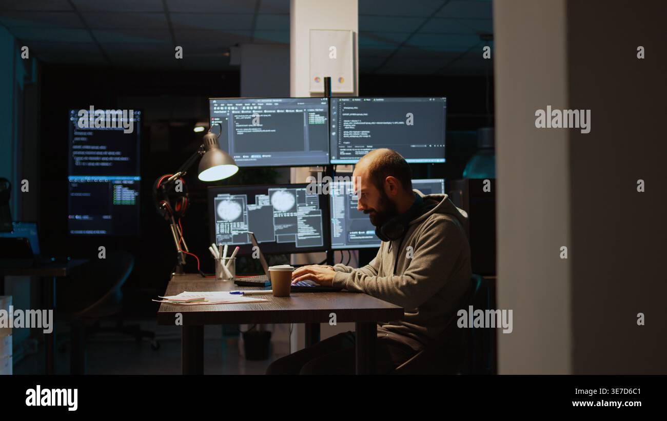 Software developer typing source code on laptop and multiple monitors, using programming language to create firewall security server. Male coder developing database cloud computing. Stock Photo
