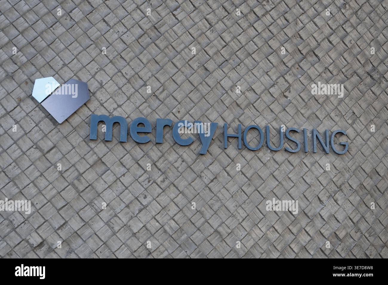 Mercy Housing logo and signage on textured exterior wall of residential ...