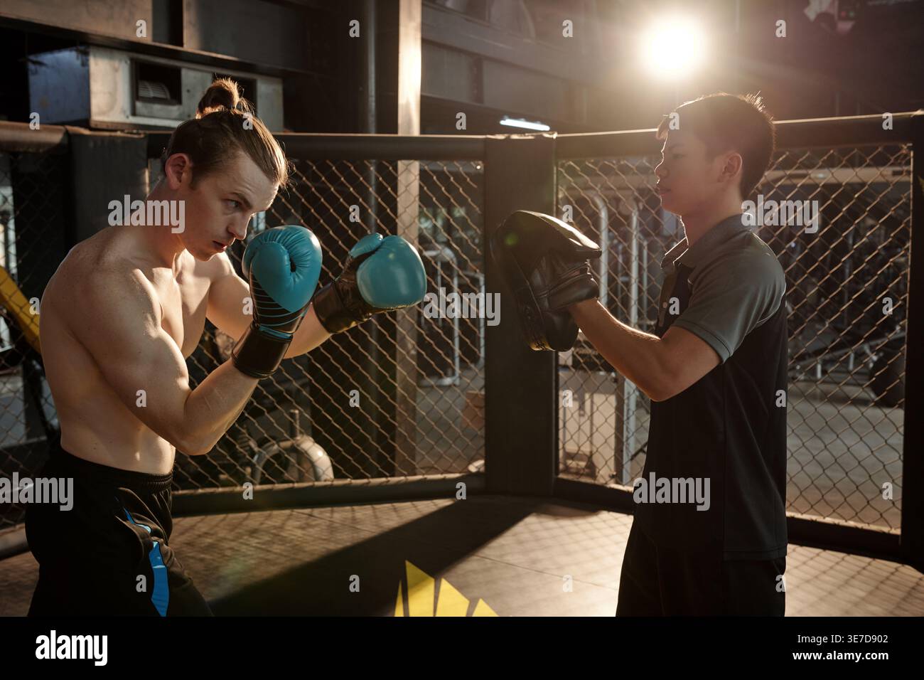 Asian male coach wearing hitting box pad training with white man ...