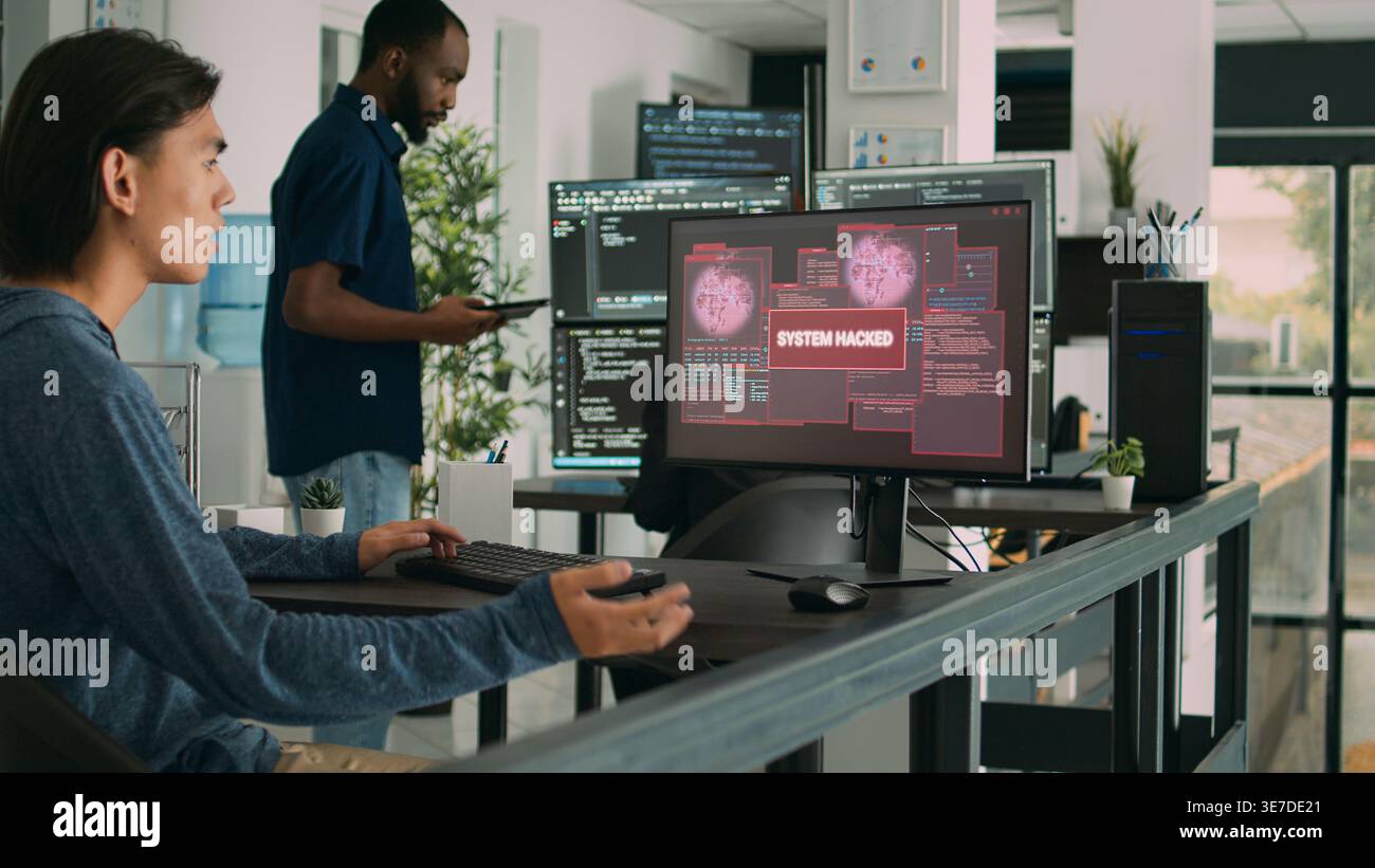 Asian programer focused on writing code encounters unexpected compiling error, being hacked in software development office. Coder having system failure and dealing with hackers. Stock Photo