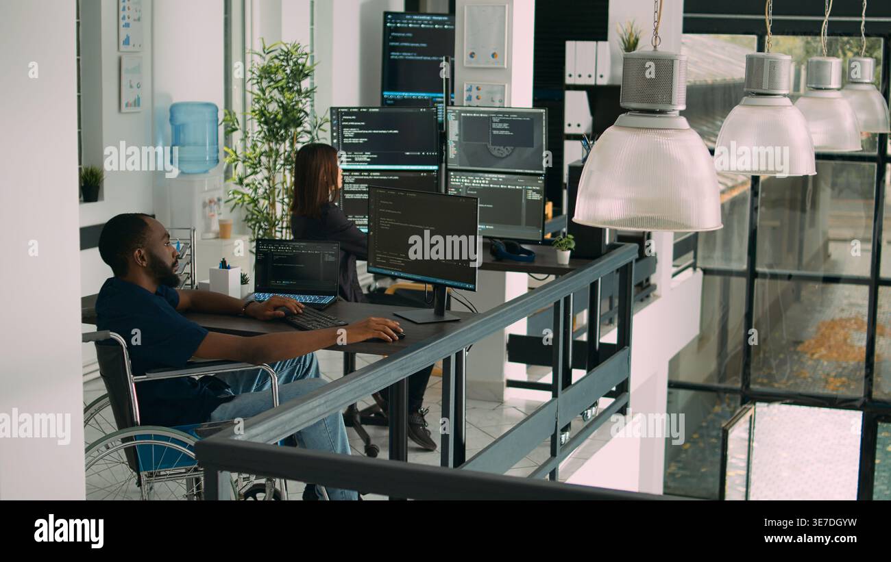 African american developer with impairment using computer to write code, parsing algorithm in software agency. Coder working on user interface with database in disability friendly office. Stock Photo