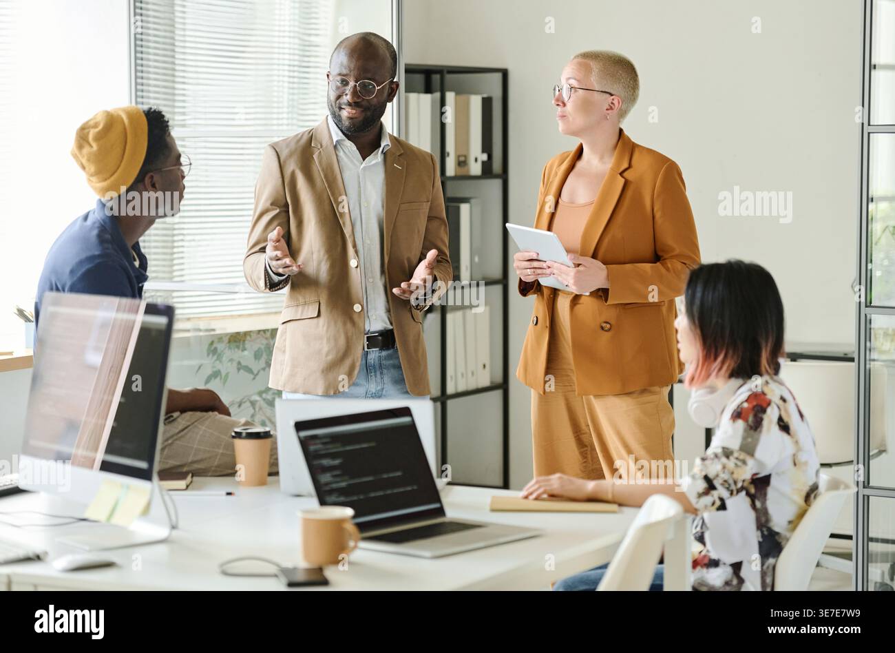 Diverse group of programmers discussing new project while standing in office Stock Photo