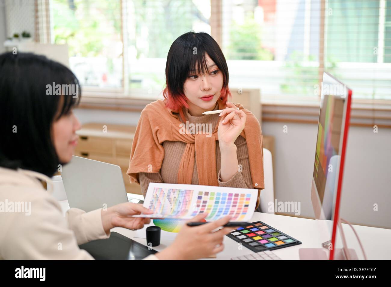 Asian female graphic designers working on their new design project while sitting at table with computer in office Stock Photo