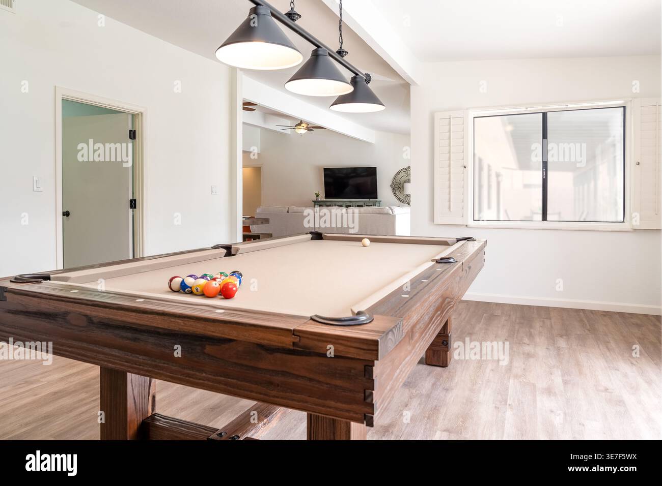 Rustic style solid wood pool table in spacious home game room with modern lighting window Stock Photo