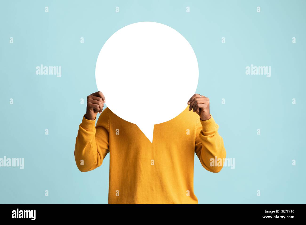 Black man hiding behind empty speech bubble standing against blue background in studio Stock Photo
