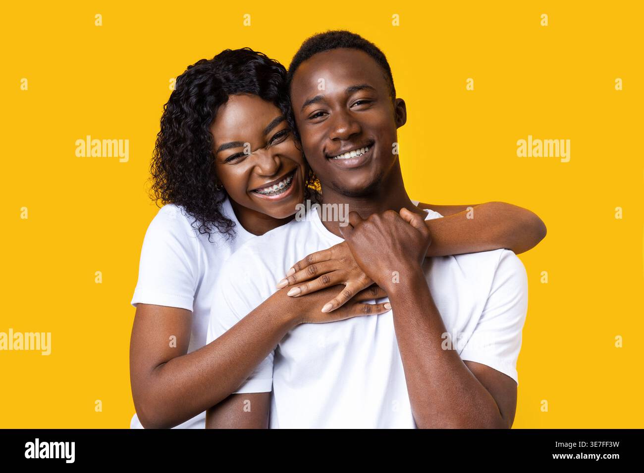 Portrait of african american young man and woman hugging on yellow ...