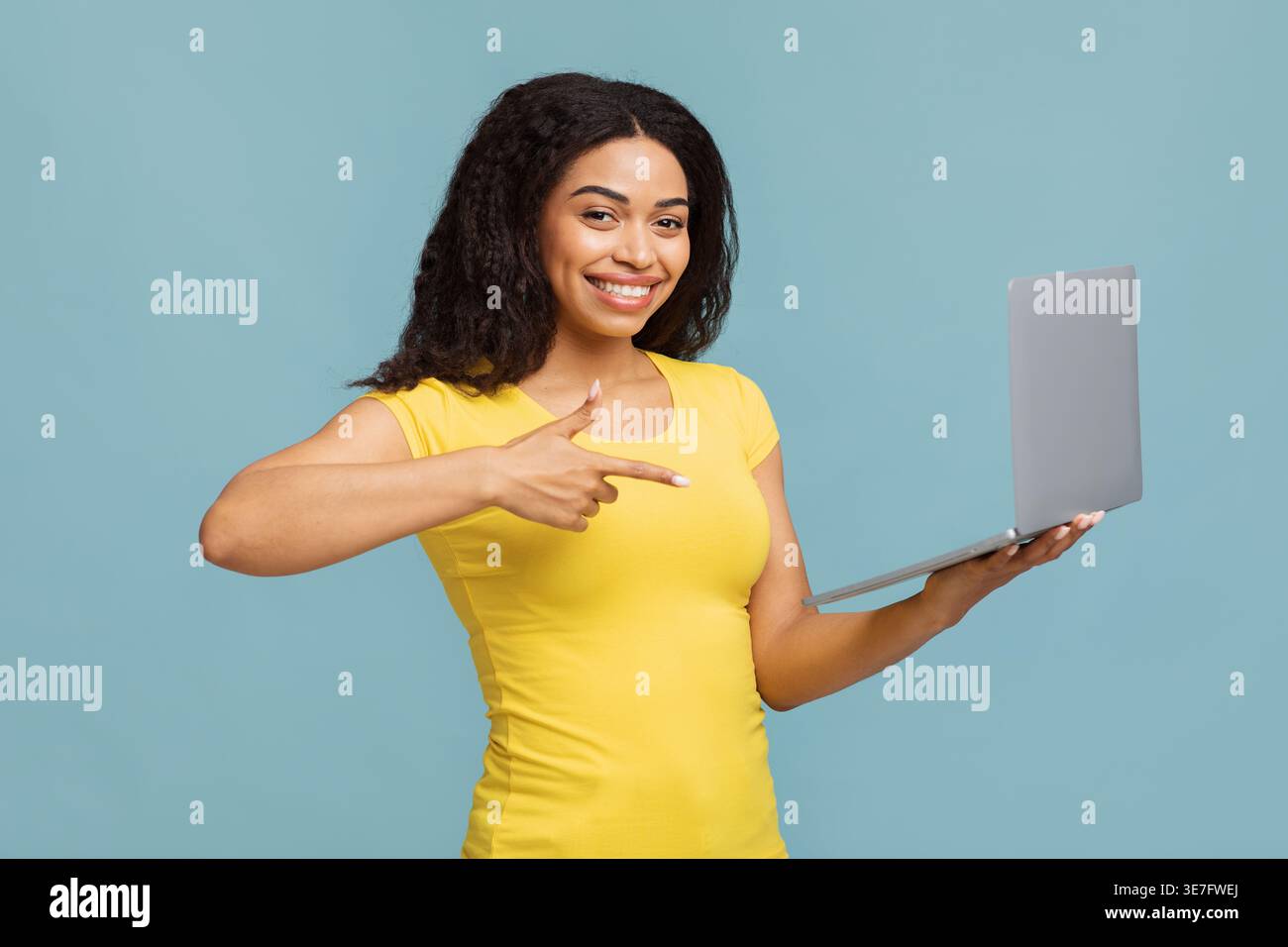Great offer. Portrait of happy lady holding laptop computer and pointing at screen, smiling at camera, happy about sales or victory, standing isolated Stock Photo