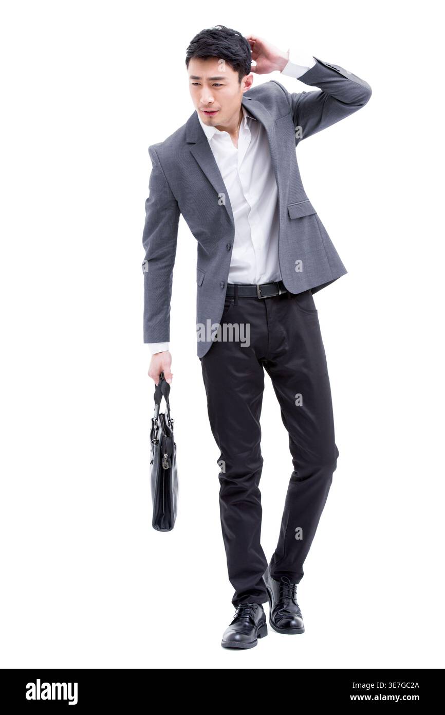 Chinese businessman holding bag scratching head standing against white background in studio Stock Photo