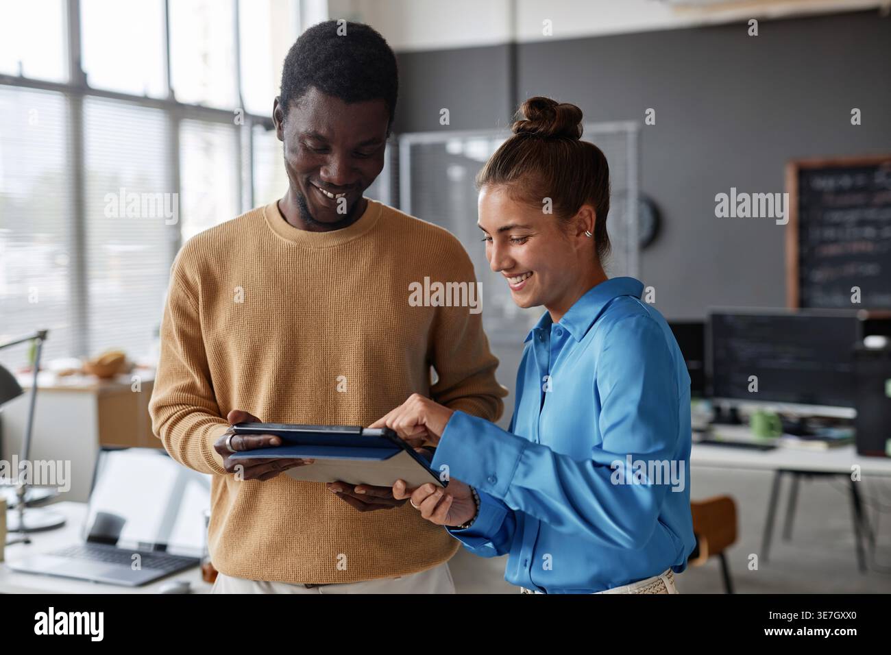 Black male and caucasian female programmers using tablet while standing in office Stock Photo